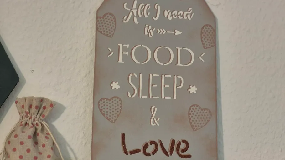 Dekoschild mit Text und Herzmustern.