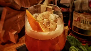 Cocktail mit Orangen- und Bananengarnitur, Holzuntergrund.