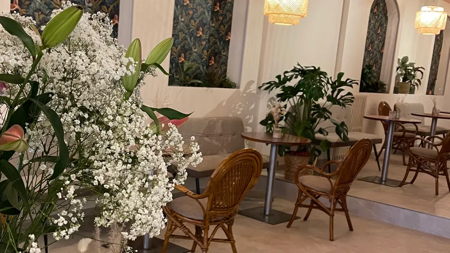 Café-Innenraum mit Blumen und Korbstühlen.