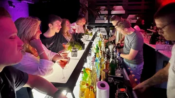 Menschen genießen Cocktails an einer Bar.