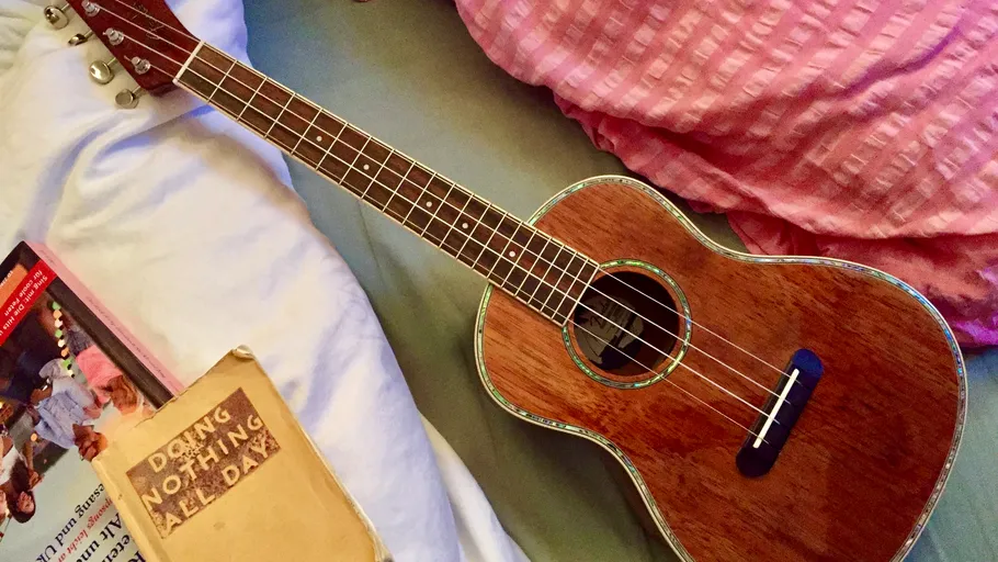 Ukulele auf Bett mit Büchern in der Nähe.