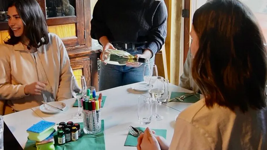 People sitting at table, one holding wine bottle.