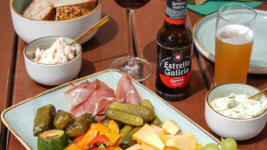 Tapas plate with drinks on wooden table.