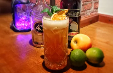 Cocktailglas mit Garnitur auf Holztisch.