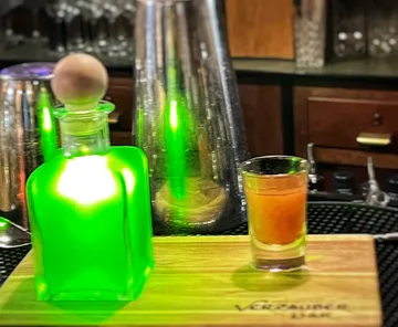 Green bottle and glass on a bar.