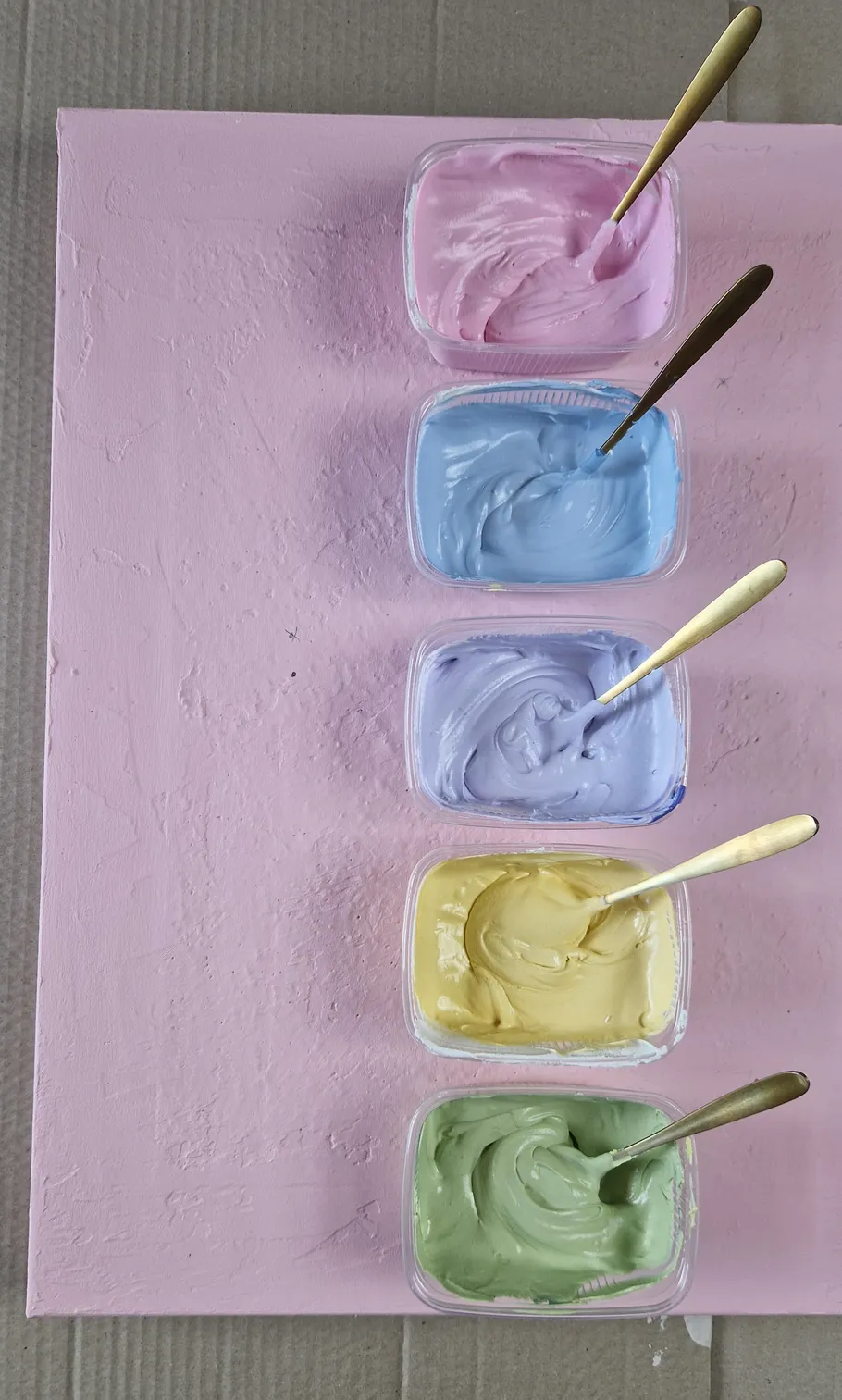 Five pastel creams in bowls with spoons.
