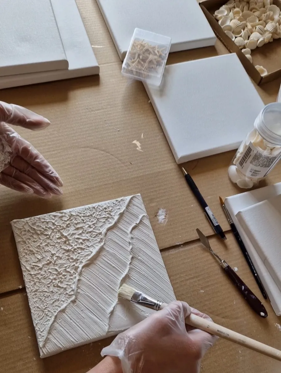 Person painting textured pattern on canvas.