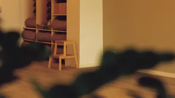 Yoga studio with shelves, bolsters, and stool.