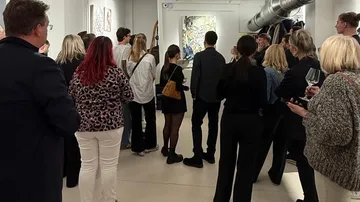 Menschenmenge beobachtet Kunstwerk in Galerieumgebung.