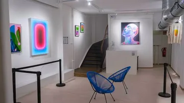 Art gallery interior with colorful paintings displayed.