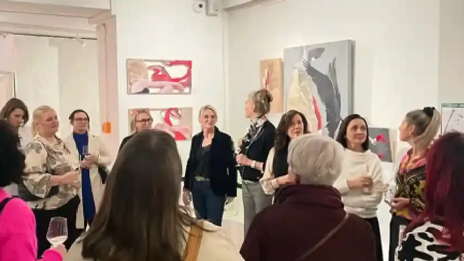 People standing in an art gallery, viewing artwork.