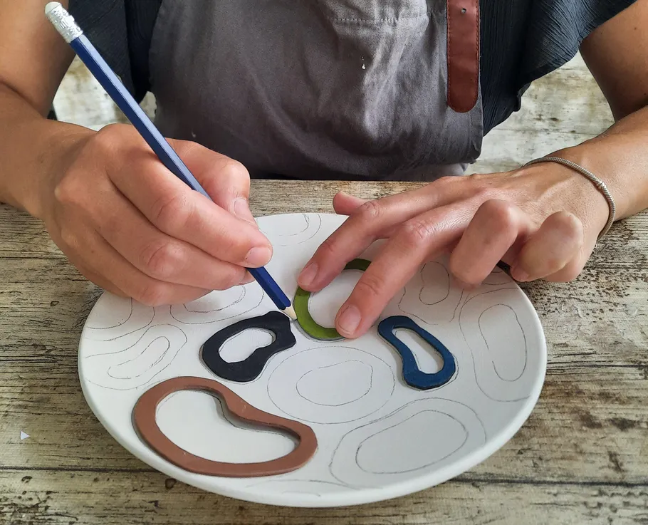 Person tracing shapes on a decorated plate.