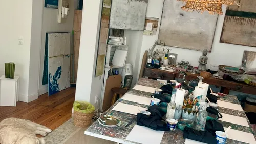 Kunststudio mit Tisch, Gemälden und Hund.