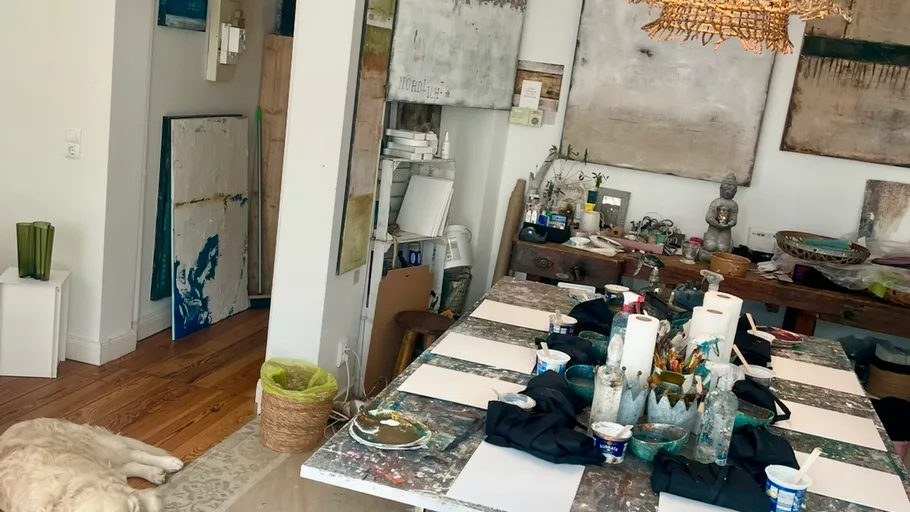 Art studio with table, paintings, and dog.