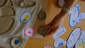 Hand hält Tonschale mit gemalten Designs.