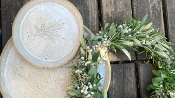 Ceramic plates with greenery on wooden table.