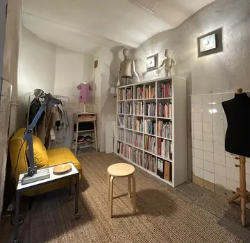 Gemütlicher Raum mit Bücherregalen, Mannequins und Sofa.
