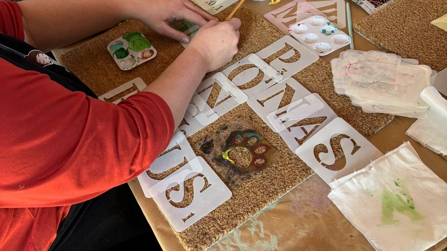 Person painting a doormat with stencils.