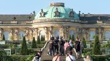 People walking towards ornate palace building.