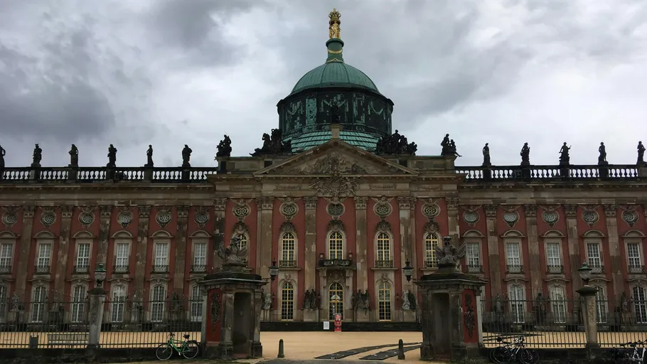 Baroque palace with statues under cloudy sky.