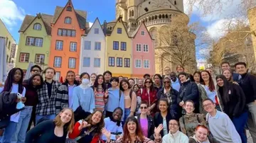 Group posing with colorful buildings and church.