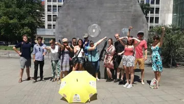Group posing near large circular sculpture outdoors.