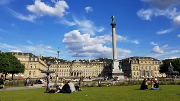 People relaxing in front of historic building.