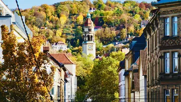 Tower in city with hill and trees.