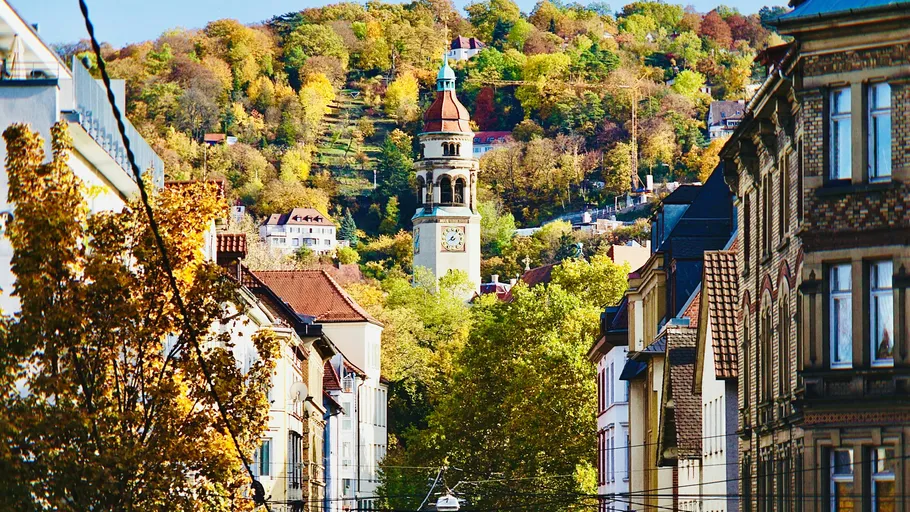 Tower in city with hill and trees.