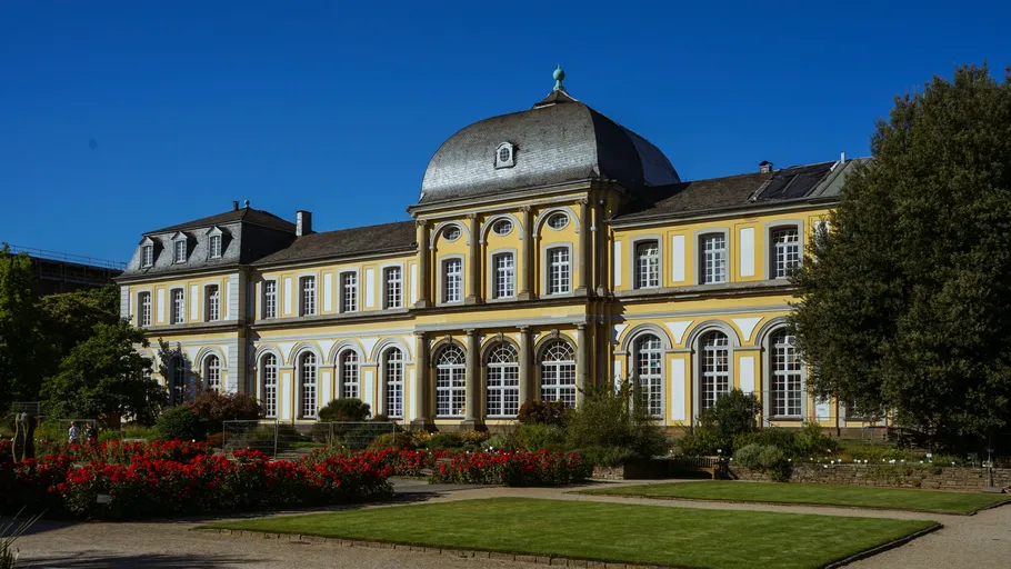 Historic building with arched windows and gardens.