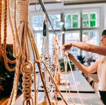 Person making macramé in a workshop setting.