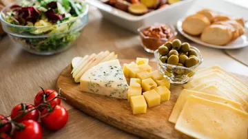 Käse und Oliven auf einem Holzbrett.