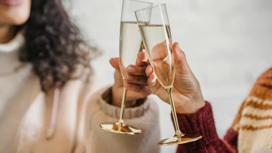 Two people clinking champagne glasses indoors.