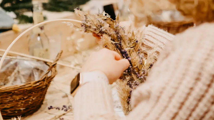 Person crafting with dried flowers indoors.