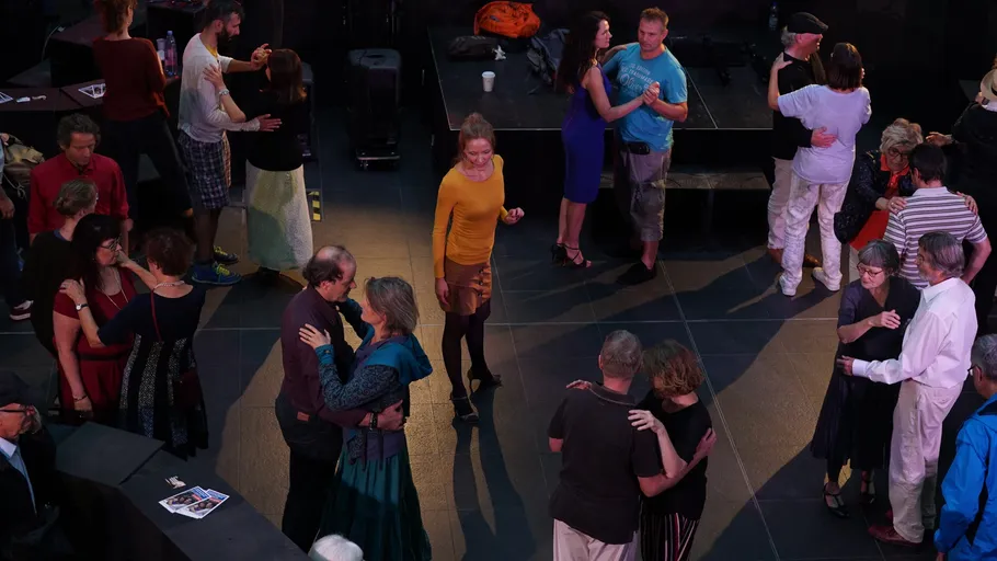 People dancing together on a dark floor.