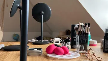 Makeup tools and mirror on wooden table.