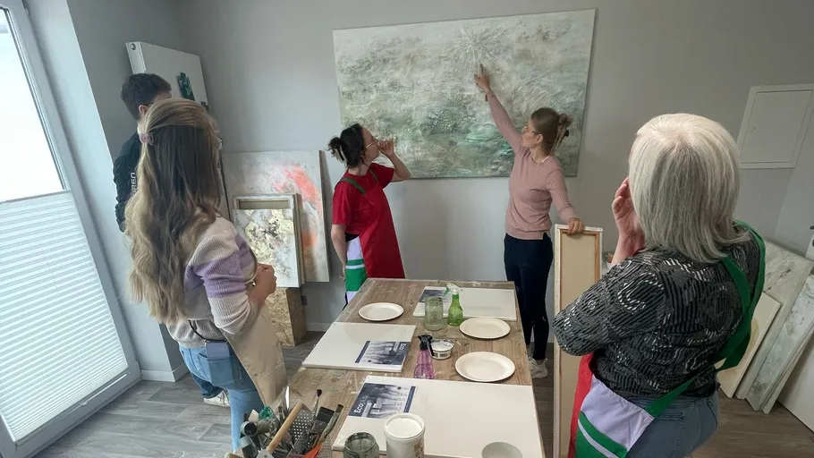 Personen diskutieren Kunstwerk in einem Atelier.