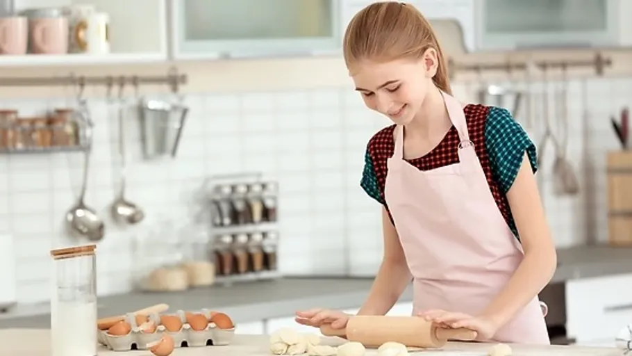 Girl rolling dough in a kitchen.
