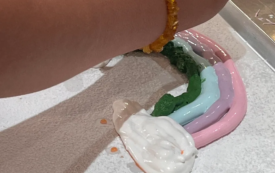 Hand painting rainbow shapes with whipped cream.