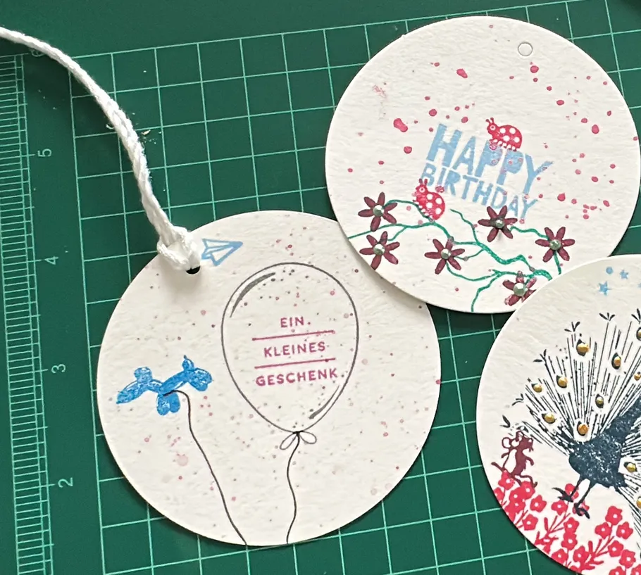 Runde Geschenkanhänger mit verschiedenen Designs auf Schneidematte.