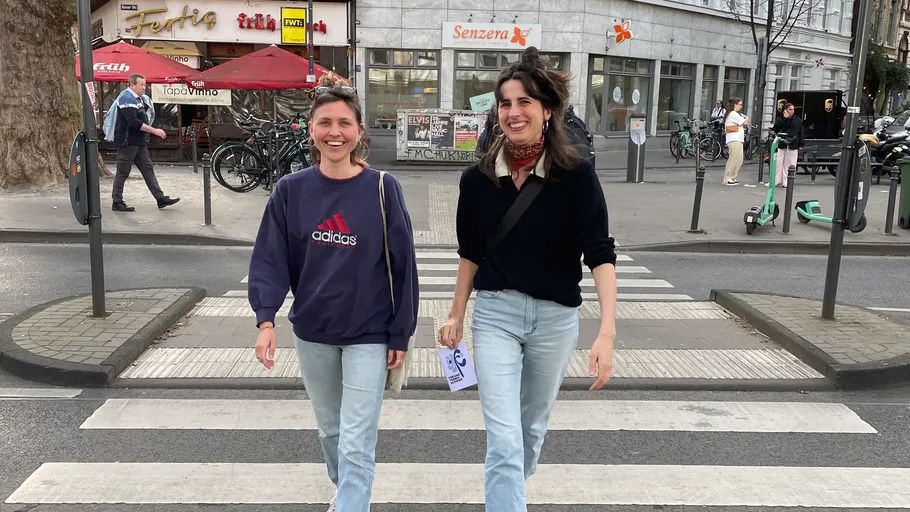Two women walking on a city crosswalk.