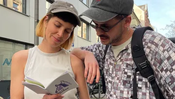 Two people reading a booklet outdoors.