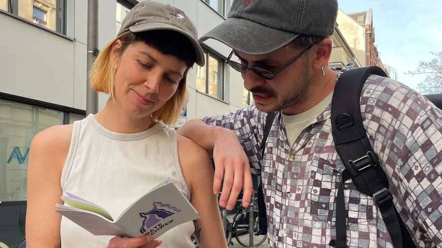 Two people reading a booklet outdoors.