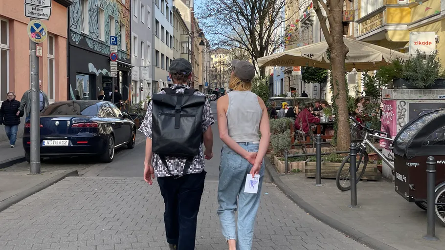 Zwei Personen gehen auf einer belebten Straße.