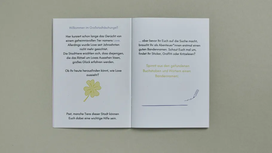Offenes Heft mit deutschem Text und Kleeblatt.