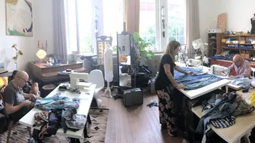 People sewing in a bright room with equipment.