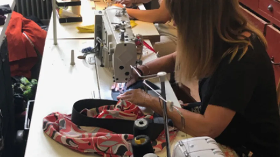 Person sewing fabric using a sewing machine.