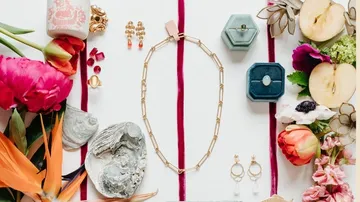 Schmuck und Blumen auf weißem Hintergrund angeordnet.