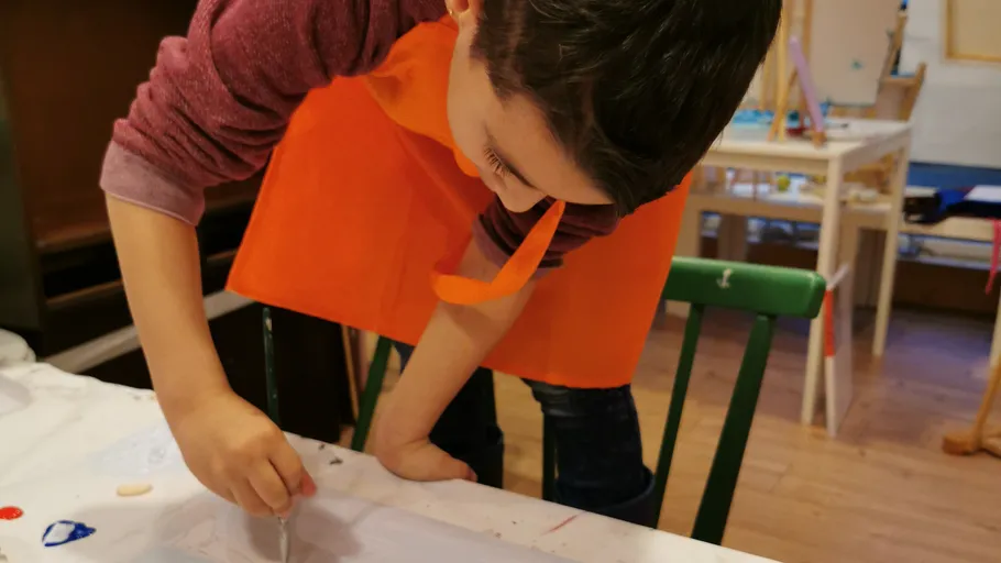 Child painting on paper in art classroom.