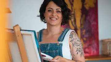 Woman painting on canvas in art studio.